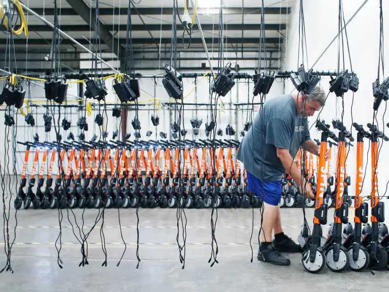 Spin electric scooters and an adult man in blue shorts